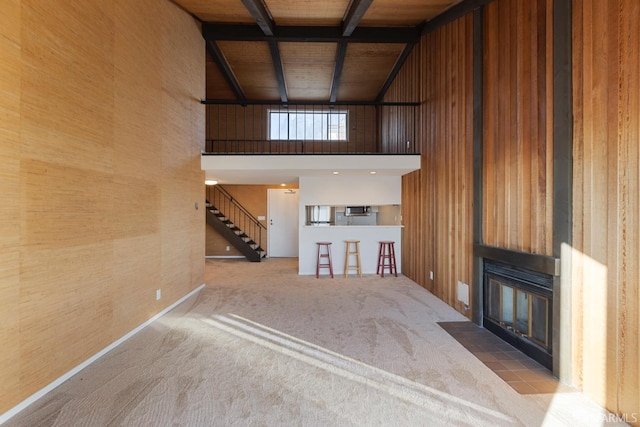 unfurnished living room with wood walls, coffered ceiling, wooden ceiling, carpet floors, and beamed ceiling