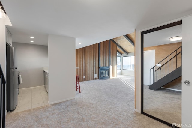 interior space featuring recessed lighting, a glass covered fireplace, light carpet, wood walls, and stairs