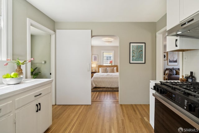 600 Ellsworth St, San Francisco, CA 94110 - kitchen with under cabinet range hood, black range with gas cooktop, light wood-style floors, white cabinets, and open floor plan