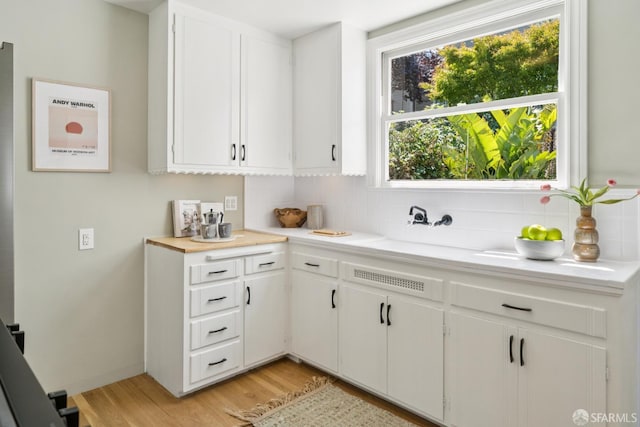 600 Ellsworth St, San Francisco, CA 94110 - kitchen with backsplash, light countertops, light wood-style flooring, and white cabinetry