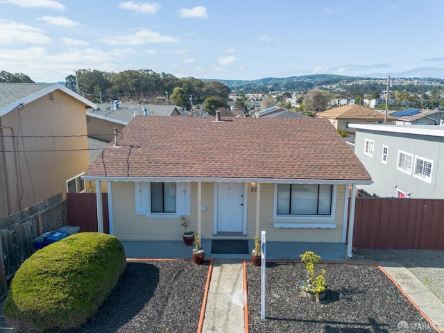 ranch-style house featuring roof with shingles and fence