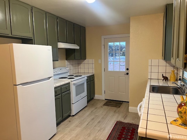 kitchen featuring white appliances, green cabinets, and tile counters