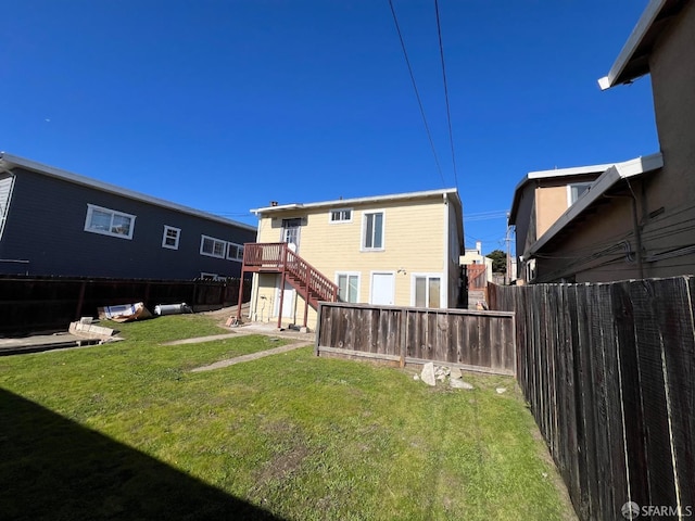 back of house with stairs, a fenced backyard, and a lawn