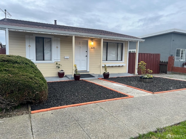 view of front of home featuring roof with shingles and fence