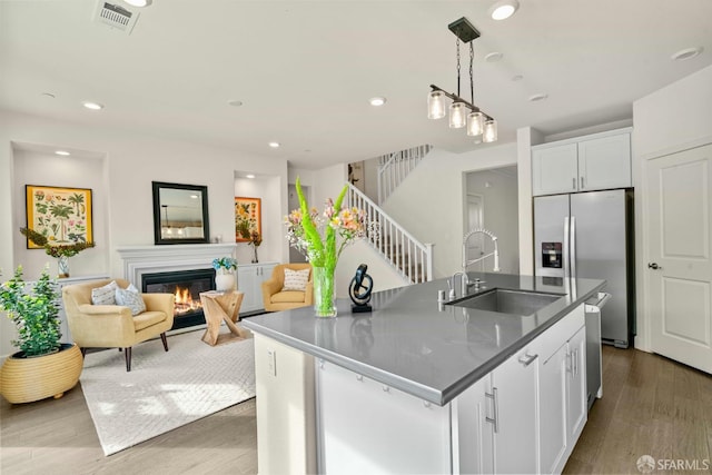 382 Crestview Cir, Daly City, CA 94015 - kitchen with stainless steel fridge, dark countertops, white cabinetry, a glass covered fireplace, and wood finished floors