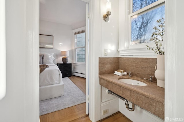 bathroom with parquet flooring, a baseboard radiator, a wealth of natural light, and sink