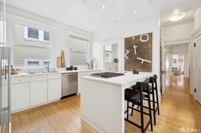 kitchen featuring white cabinets, a breakfast bar area, light hardwood / wood-style flooring, kitchen peninsula, and stainless steel appliances