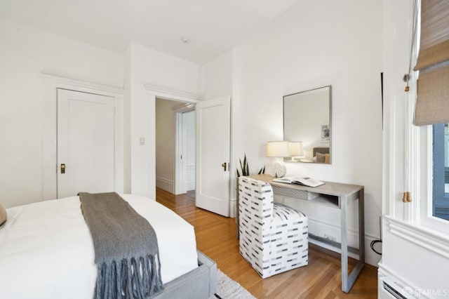 bedroom with a baseboard heating unit and light hardwood / wood-style flooring