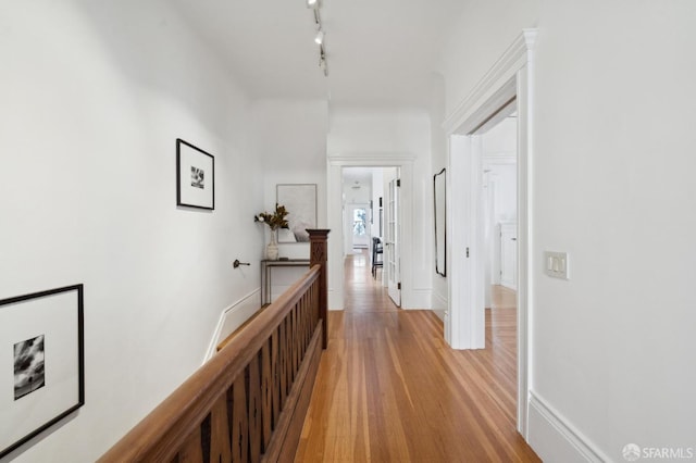 hallway featuring light wood-type flooring and rail lighting