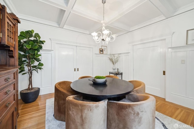 dining room with beamed ceiling, light hardwood / wood-style floors, coffered ceiling, and an inviting chandelier