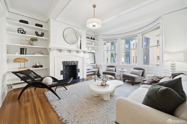 living room with hardwood / wood-style flooring, built in shelves, and a brick fireplace