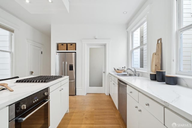 kitchen with white cabinets, stainless steel appliances, light hardwood / wood-style floors, and sink