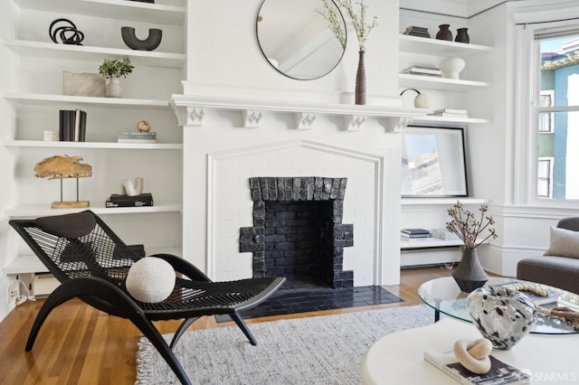 sitting room with built in features, a brick fireplace, and a wealth of natural light