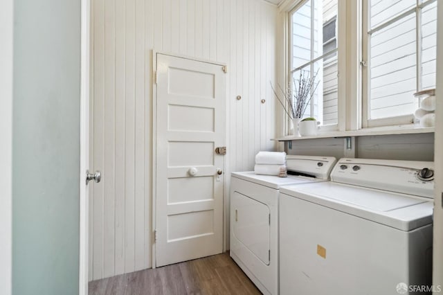 washroom with wood walls, light hardwood / wood-style flooring, and washer and dryer