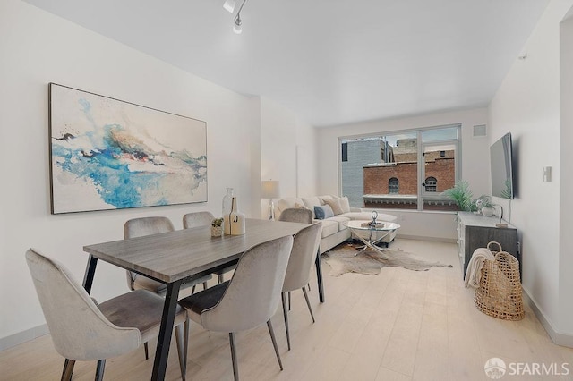 dining room featuring light wood-style flooring and baseboards