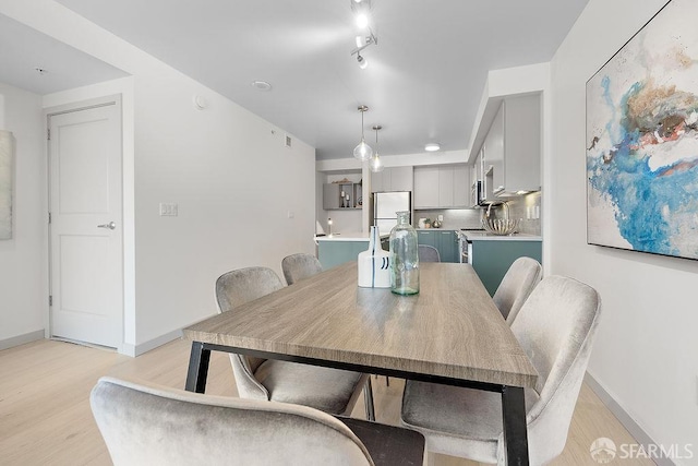 dining space with light wood-style flooring and baseboards