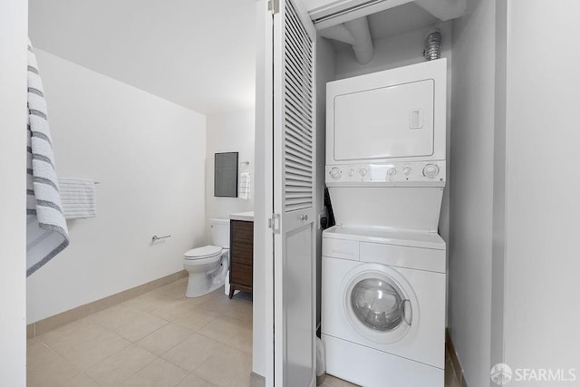 washroom featuring stacked washer and clothes dryer and baseboards