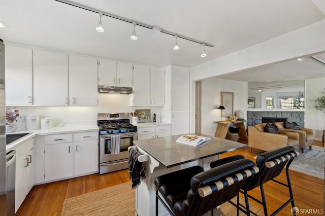 kitchen featuring stainless steel appliances, a breakfast bar, white cabinets, and light wood-type flooring