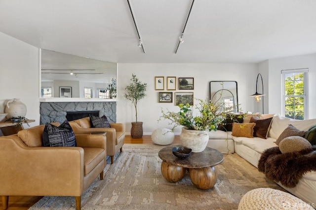 living room with track lighting, a fireplace, and light wood-type flooring