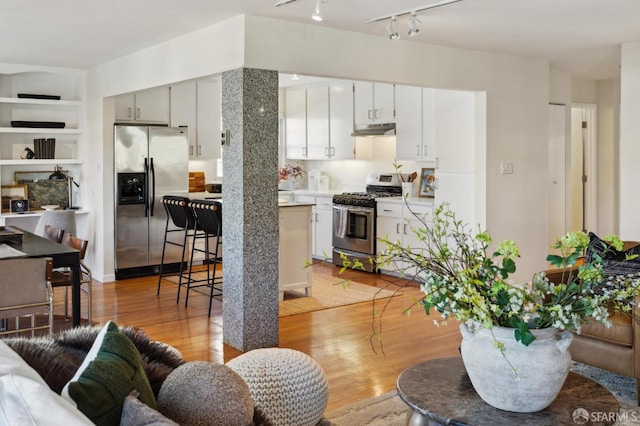 kitchen with built in shelves, light wood-type flooring, white cabinets, and appliances with stainless steel finishes