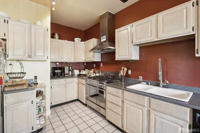 kitchen featuring light tile patterned floors, wall chimney exhaust hood, sink, and stainless steel stove