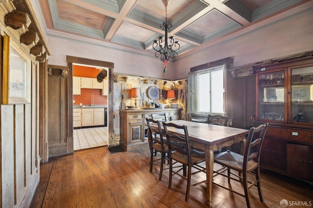 dining room featuring crown molding, dark wood-type flooring, a notable chandelier, sink, and coffered ceiling