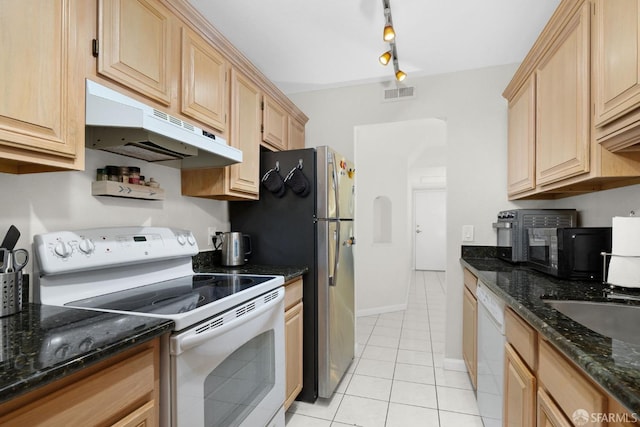 kitchen with white appliances, light brown cabinets, track lighting, light tile patterned floors, and dark stone counters