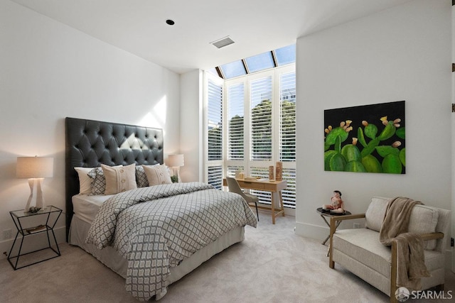 bedroom featuring baseboards, a wall of windows, visible vents, and light colored carpet