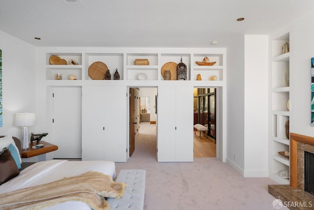 bedroom featuring light colored carpet, baseboards, and a premium fireplace