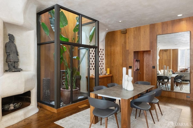 dining area featuring wood finished floors and wooden walls