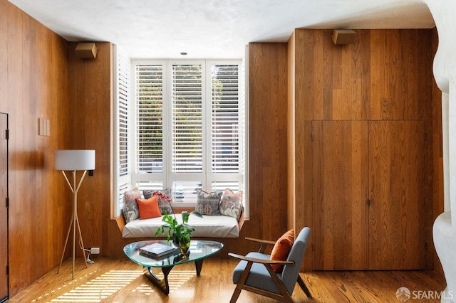 sitting room featuring wood walls, wood finished floors, and a healthy amount of sunlight