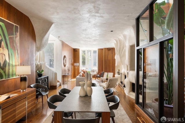 dining area with expansive windows, a fireplace, and wood finished floors