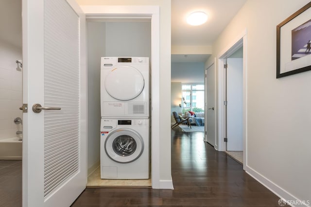 laundry area featuring stacked washer / dryer and dark hardwood / wood-style flooring