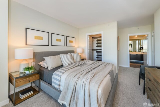 carpeted bedroom with a spacious closet, ensuite bathroom, and a closet