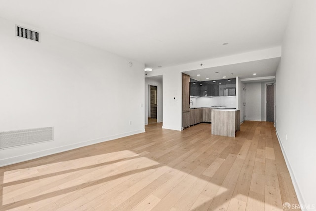 unfurnished living room featuring light wood finished floors, visible vents, and baseboards