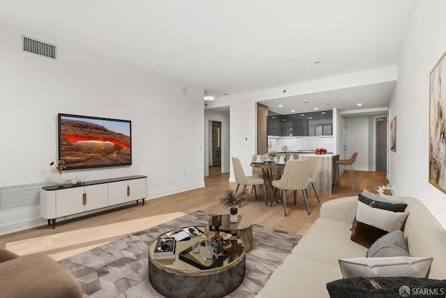 living room with light wood-style floors, baseboards, and visible vents