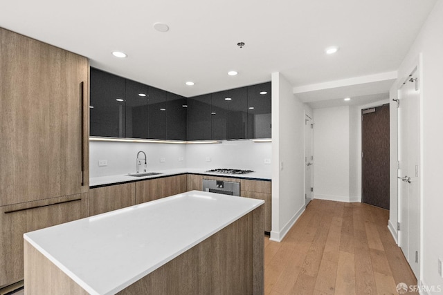 kitchen with gas stovetop, recessed lighting, light wood-style flooring, a sink, and modern cabinets