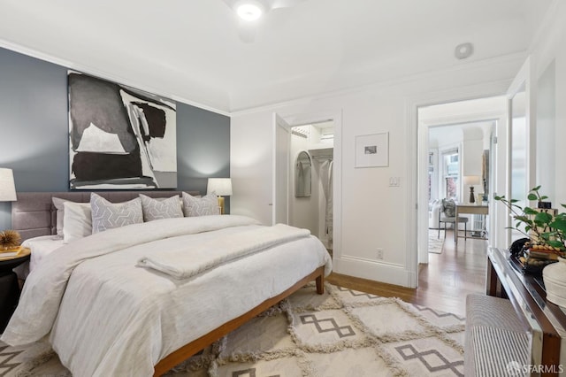 bedroom with crown molding, baseboards, and wood finished floors