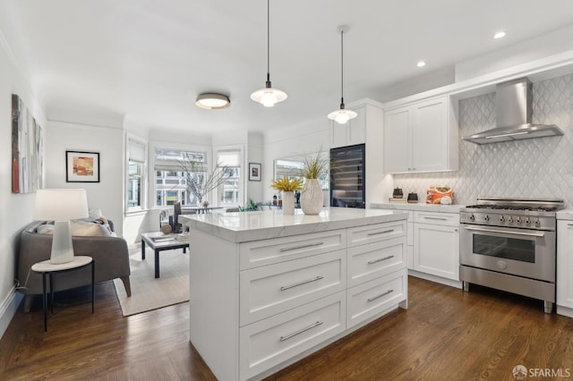 kitchen with wall chimney range hood, stainless steel range, dark wood finished floors, and tasteful backsplash