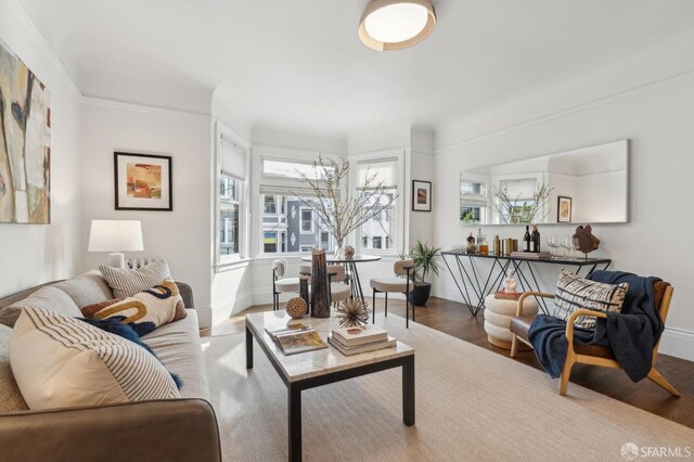 living area with crown molding, baseboards, and wood finished floors