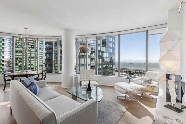 living room featuring a view of city, wood finished floors, a water view, and a chandelier