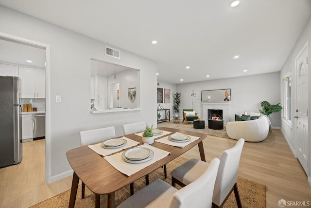 dining space with light hardwood / wood-style floors and a fireplace