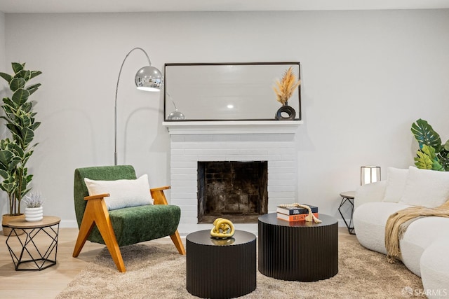 living room with a brick fireplace and light wood-type flooring