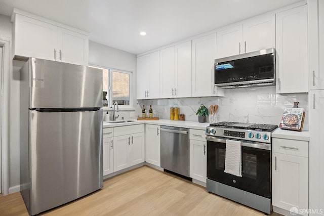 kitchen with sink, stainless steel appliances, white cabinets, and backsplash