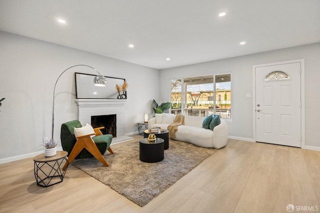 living room with a brick fireplace and light wood-type flooring