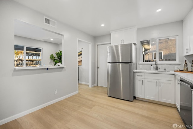 kitchen featuring sink, white cabinetry, light wood-type flooring, and appliances with stainless steel finishes