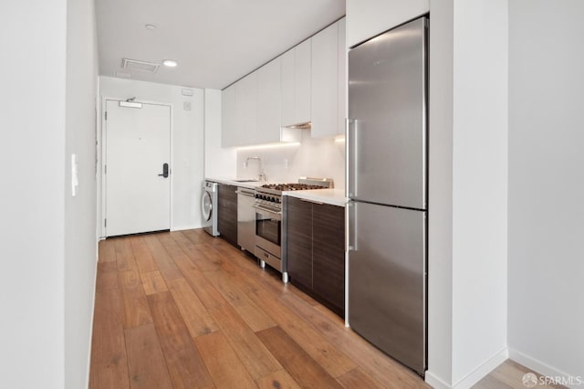 1433 Bush St Unit 702, San Francisco, CA 94109 - kitchen featuring white cabinets, light wood-type flooring, washer / dryer, high quality appliances, and dark brown cabinetry