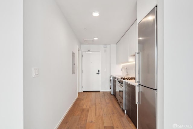 1433 Bush St Unit 702, San Francisco, CA 94109 - kitchen featuring premium appliances, light hardwood / wood-style flooring, sink, and white cabinetry