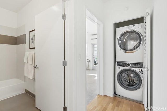 laundry area featuring stacked washer / drying machine and light wood-type flooring