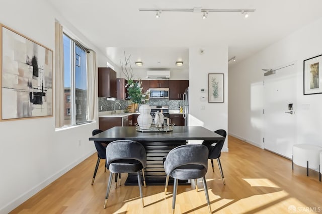 dining space featuring sink, light hardwood / wood-style floors, and an AC wall unit